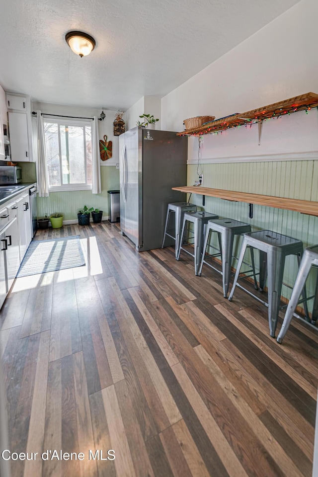 kitchen featuring hardwood / wood-style floors, a textured ceiling, white cabinets, and stainless steel appliances