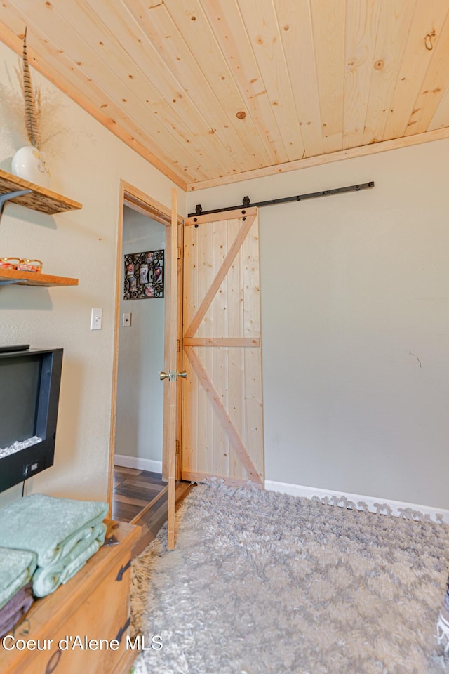 unfurnished bedroom featuring a barn door, wood finished floors, and wood ceiling