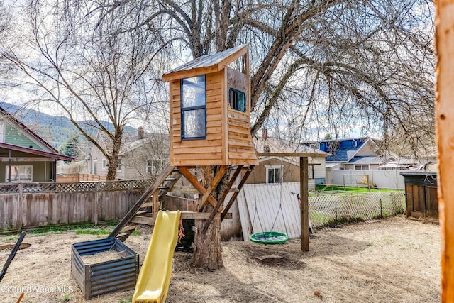 view of jungle gym with a mountain view and a fenced backyard