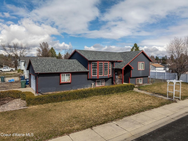 view of front facade featuring an attached garage, a shingled roof, a front yard, and fence