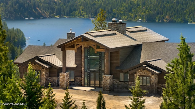 4579 E Plum Rd, Coeur Dalene, ID 83814 - view of front of home with a view of trees, a chimney, roof with shingles, and stone siding