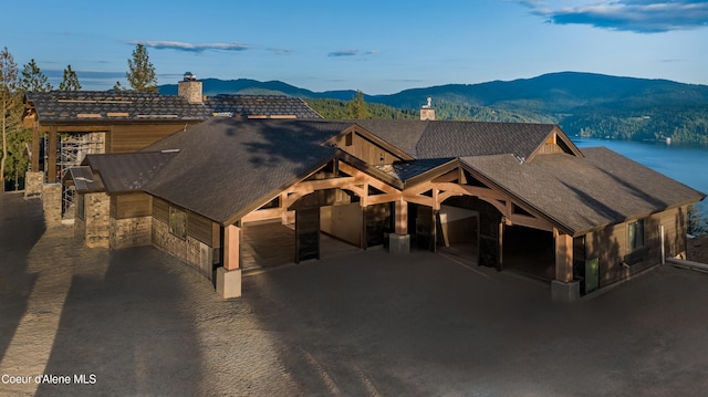 4579 E Plum Rd, Coeur Dalene, ID 83814 - view of front of property with a chimney, a mountain view, an attached garage, and stone siding