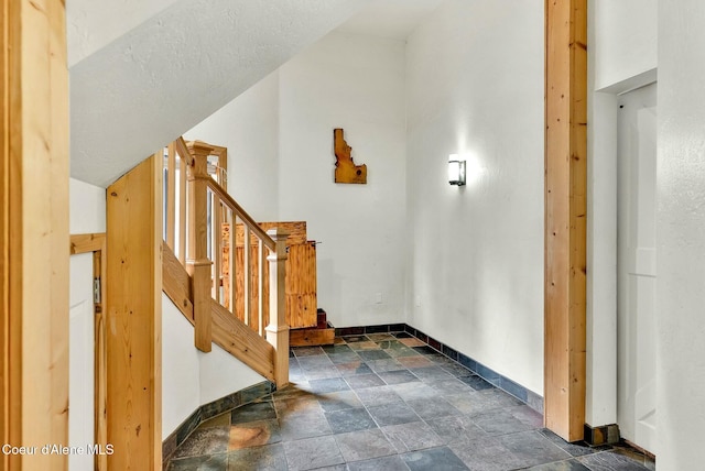 interior space with stairs, stone finish floor, and baseboards