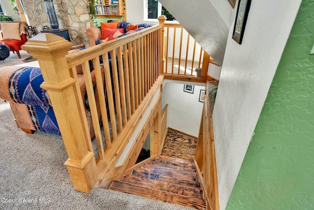 stairway with a wood stove, carpet, and a textured wall