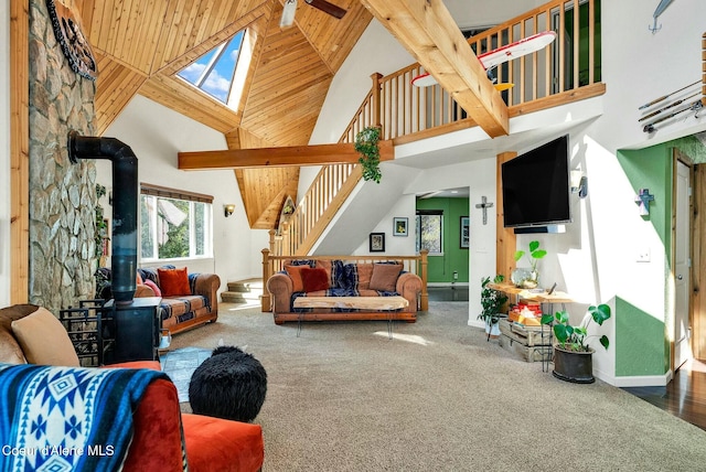 carpeted living room with a towering ceiling, baseboards, wooden ceiling, and a wood stove