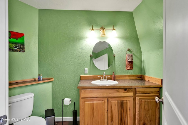 half bath with toilet, vanity, and a textured wall
