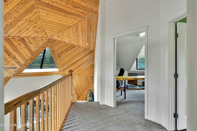 hall featuring carpet flooring, a healthy amount of sunlight, wood ceiling, and vaulted ceiling