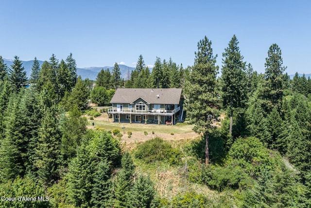 back of house with a deck with mountain view and a forest view