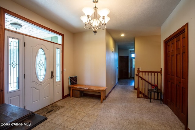 foyer entrance with baseboards, light tile patterned flooring, a textured ceiling, light colored carpet, and a chandelier