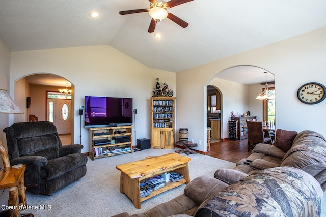 carpeted living room with arched walkways, ceiling fan with notable chandelier, and vaulted ceiling