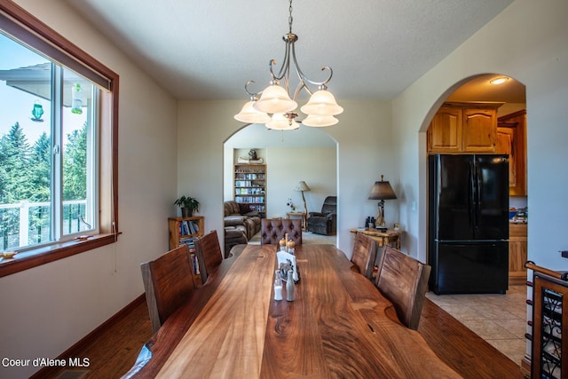 dining room with arched walkways, a chandelier, and light tile patterned flooring