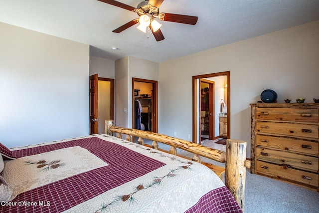 bedroom with a spacious closet, ceiling fan, carpet floors, a closet, and ensuite bath