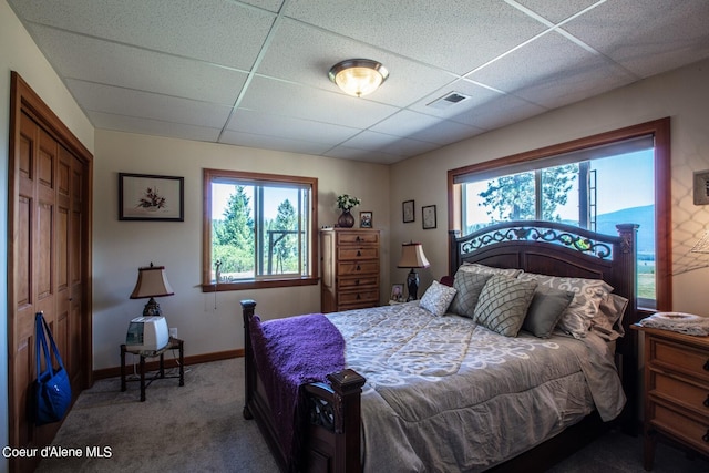 carpeted bedroom with a drop ceiling, baseboards, and visible vents