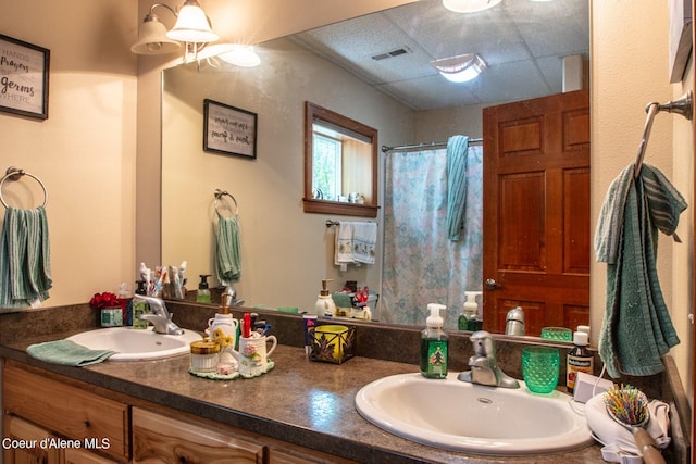 full bath featuring double vanity, a shower with curtain, visible vents, and a sink
