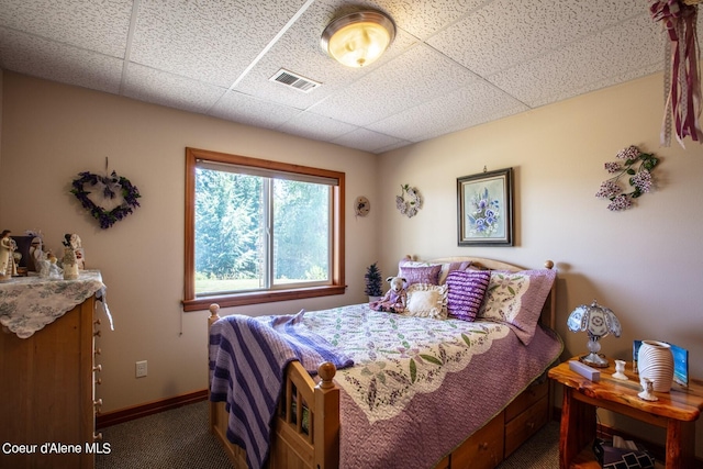carpeted bedroom featuring visible vents, baseboards, and a drop ceiling