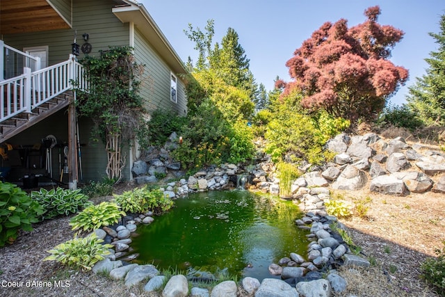 view of yard featuring a garden pond and stairs