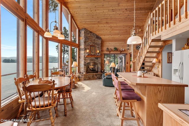 190 W Eagle Crest Dr, Coeur Dalene, ID 83814 - carpeted dining room featuring a stone fireplace, wooden ceiling, a water view, and high vaulted ceiling
