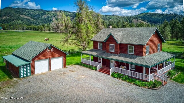 415 Shale Rd, Priest River, ID 83856 - view of front of home featuring covered porch, an outbuilding, a view of trees, a mountain view, and roof with shingles