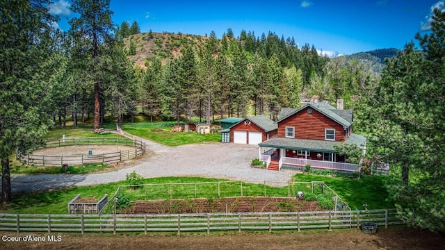 415 Shale Rd, Priest River, ID 83856 - back of property featuring dirt driveway, a detached garage, a wooded view, a mountain view, and a porch