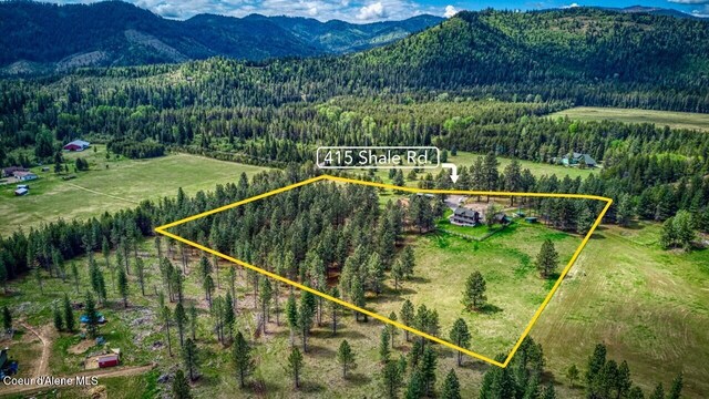 415 Shale Rd, Priest River, ID 83856 - aerial view of property and surrounding area with a heavily wooded area, a mountain backdrop, and property boundaries highlighted