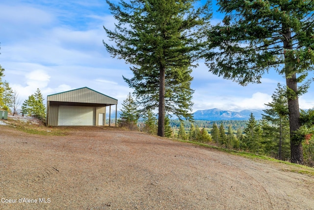 view of yard with an outbuilding, driveway, a mountain view, and a detached garage