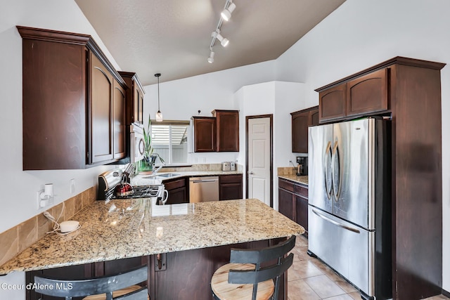 7068 N Epervier Ln, Coeur Dalene, ID 83815 - kitchen featuring stainless steel appliances, a peninsula, light stone countertops, a breakfast bar, and dark brown cabinets