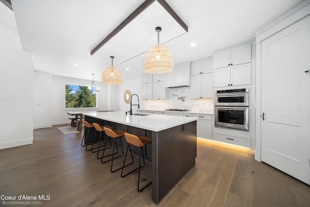 kitchen with backsplash, a sink, white cabinetry, wood finished floors, and stainless steel appliances