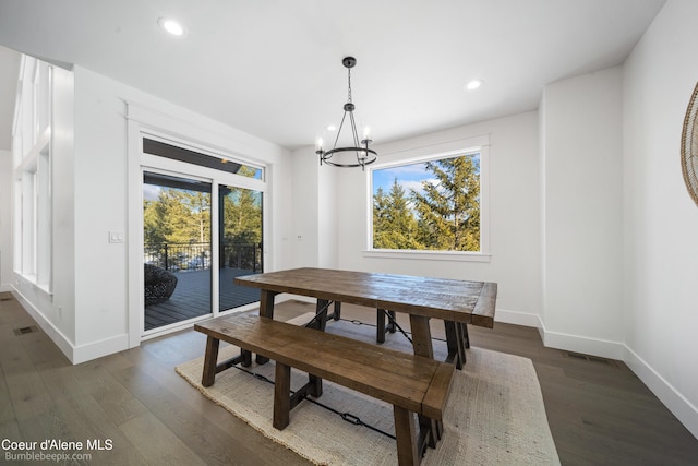 dining area featuring dark wood finished floors, a wealth of natural light, baseboards, and an inviting chandelier