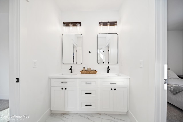 ensuite bathroom featuring marble finish floor, a sink, baseboards, and ensuite bathroom