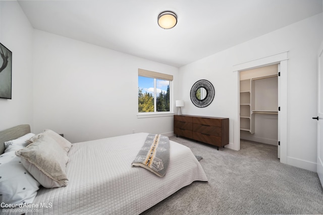 carpeted bedroom with a closet, a walk in closet, and baseboards