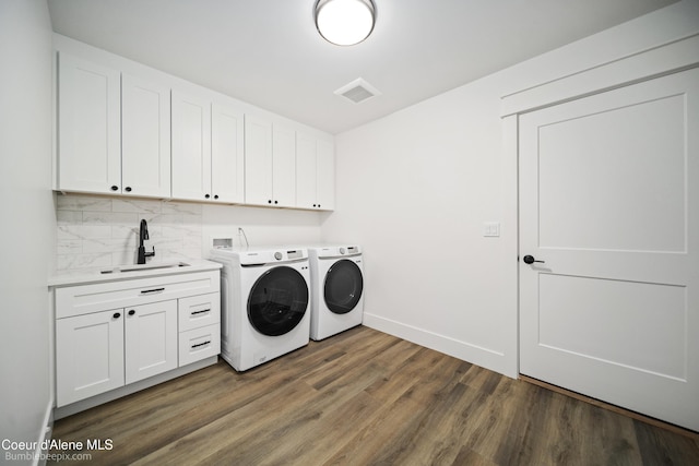 laundry room featuring a sink, separate washer and dryer, wood finished floors, visible vents, and cabinet space