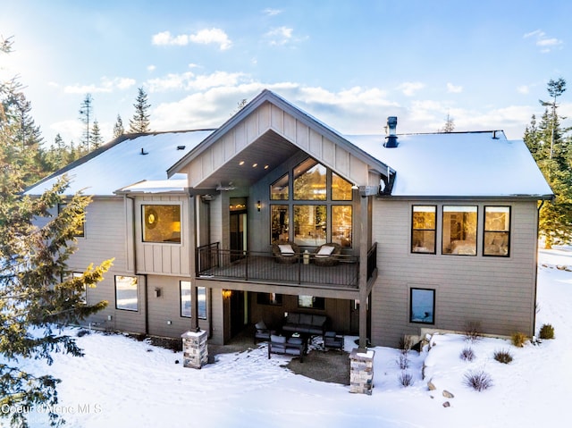 snow covered house with a balcony and outdoor lounge area