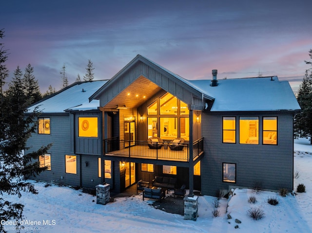 snow covered rear of property with a balcony and an outdoor living space