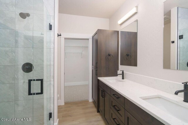 7279 N Grafton St, Coeur Dalene, ID 83815 - full bathroom featuring a shower stall, wood finished floors, a walk in closet, and double vanity