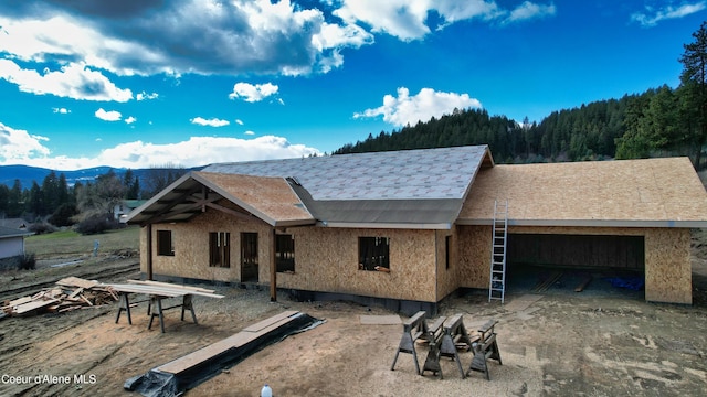 view of front of home with an attached garage, a mountain view, stucco siding, and a wooded view