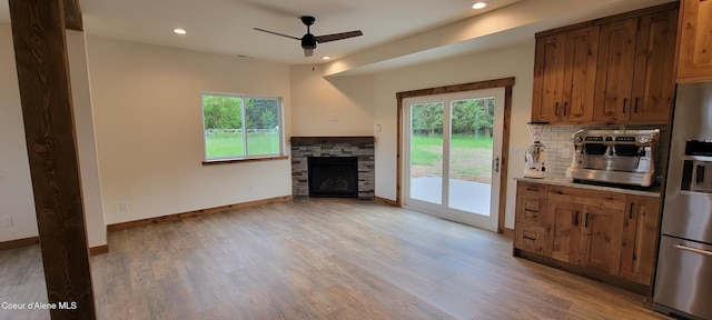 unfurnished living room featuring a fireplace, light wood-style flooring, a ceiling fan, baseboards, and recessed lighting
