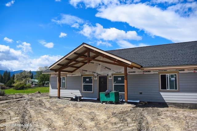 view of front of house with a porch, roof with shingles, and a mountain view