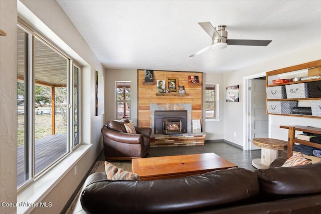 living room with a large fireplace, dark wood-type flooring, baseboards, and ceiling fan