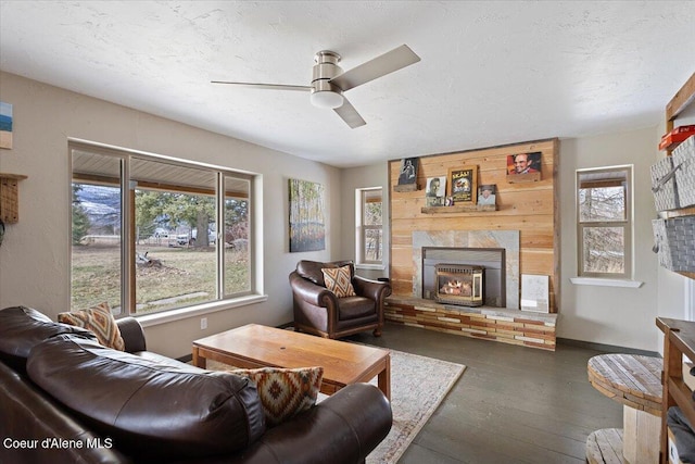living area featuring dark wood-style floors, a fireplace, a ceiling fan, and a healthy amount of sunlight