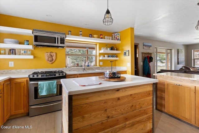 kitchen featuring a sink, open shelves, a kitchen island, and appliances with stainless steel finishes