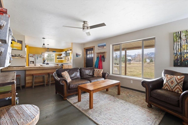 living room featuring baseboards, a textured ceiling, wood finished floors, and a ceiling fan