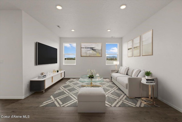 living room featuring visible vents, baseboards, a textured ceiling, recessed lighting, and wood finished floors