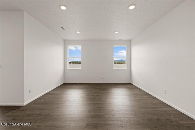 unfurnished room featuring visible vents, baseboards, dark wood-style flooring, a textured ceiling, and recessed lighting