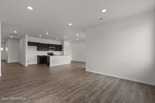 unfurnished living room with dark wood-style flooring, a sink, visible vents, and recessed lighting