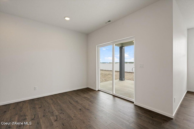 spare room featuring visible vents, dark wood-style flooring, baseboards, and a textured ceiling