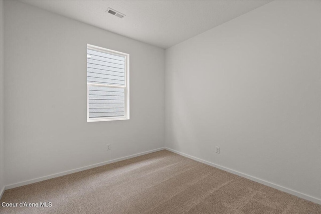 empty room featuring carpet, visible vents, and baseboards