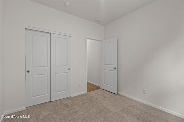 unfurnished bedroom with carpet, visible vents, a closet, and baseboards