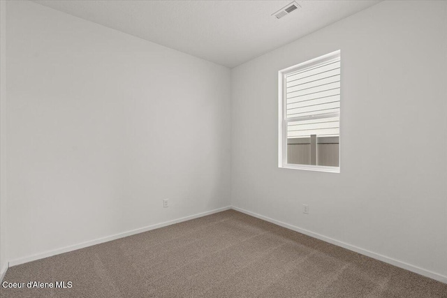 carpeted spare room featuring visible vents and baseboards