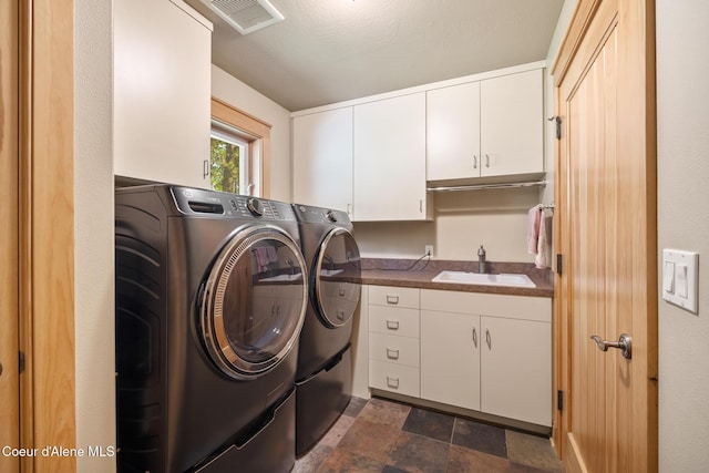 4459 E Ogara Rd, Harrison, ID 83833 - laundry room featuring washer and clothes dryer, a sink, stone finish floor, visible vents, and cabinet space