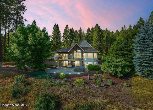 4459 E Ogara Rd, Harrison, ID 83833 - back of house at dusk with stone siding and a patio area